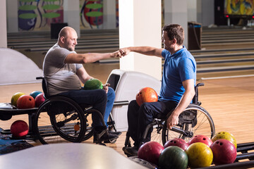 Two young disabled men in wheelchairs playing bowling in the club