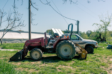 A tractor and a pickup truck face opposite directions parked in a field on a farm.