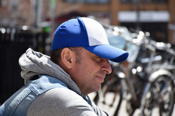 Man is sitting on a curb on city street deep in thought