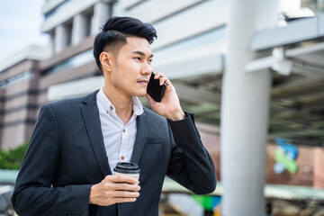 Asian businessman talking on the phone while walking to office in city