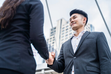 Fototapeta premium Asian business people greeting by making handshake outdoor in the city
