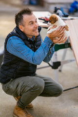 a man holding his little puppy Jack Russell in his arms