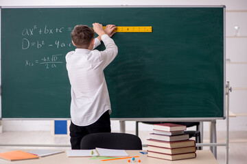 Schoolboy studying geometry in front of blackboard