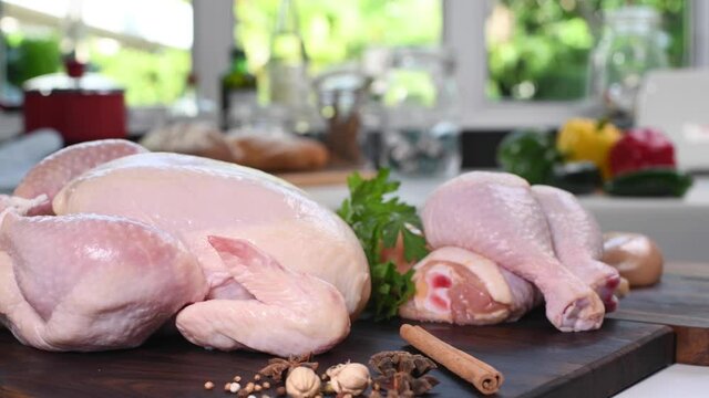 Fresh raw chicken with ingredients for cooking on a wooden cutting board in the kitchen