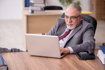 Fototapeta na wymiar Old male employee working in the office