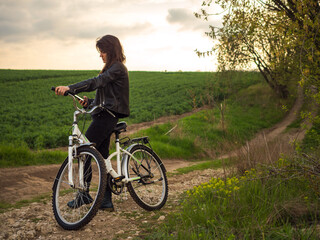 Woman with white bike outdoors in hand phone, rural road.