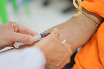puncture of a vein through the skin in order to withdraw blood for analysis.the specialist uses a syringe to venipuncture from patient's arm. selective focus                               