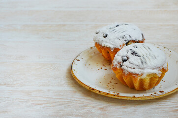 homemade cupcakes with raisins sprinkled with powdered sugar on a ceramic plate, homemade pastries and confectionery
