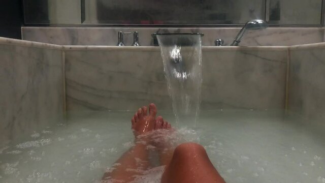 Point of view Female legs while bathing in marble bath