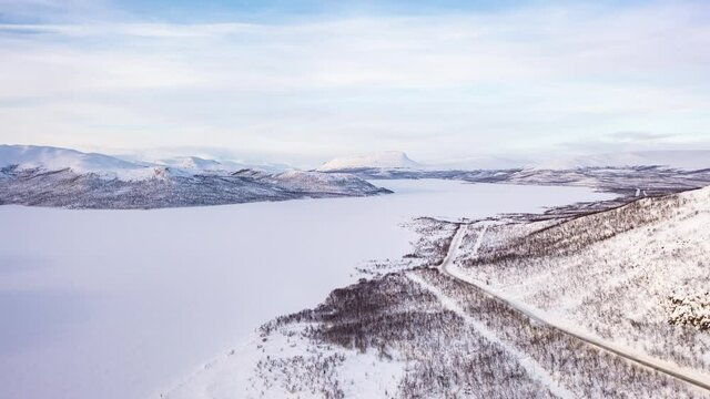Aerial hyperlapse view of a trucks driving on arctic road, Saanatunturi mountain background, in Kilpisjarvi, Lapland - motion timelapse, drone shot