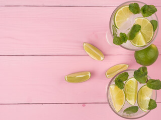 A refreshing summer drink with lime and mint Mojito stands on a pink table. Top view, copy space.