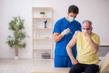 Old male patient visting young male doctor in vaccination concep