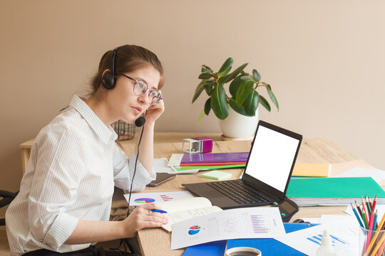 Empty space for the text. Young woman 20-25 at her workplace. A laptop with a blank white screen.