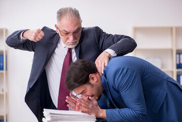Old boss and young male employee in bullying concept