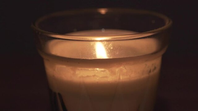 close macro view of white cream wax home candle in glass pot. fire turned off and smoke