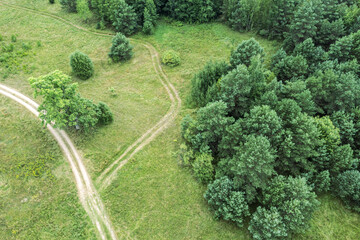 aerial view of country road through the green field and forest