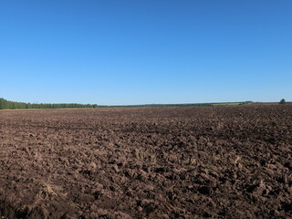 Fototapeta na wymiar The fertile soil of an arable land was paved to cultivation of a harvest, the chernozem in an organic agricultural farm. Agriculture, landscape of the farmland.