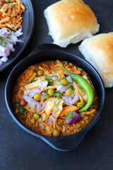 Spicy Misal Pav or usal Pav is a traditional snack or Chaat food from Maharashtra, India. Served with chopped onion, lemon wedges and farsan. Selective focus with copy space