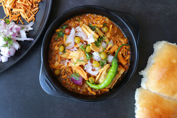 Spicy Misal Pav or usal Pav is a traditional snack or Chaat food from Maharashtra, India. Served with chopped onion, lemon wedges and farsan. Selective focus with copy space