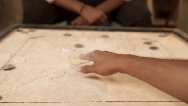 Close up POV shot of playing carrom board and placing coin in pocket