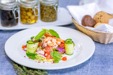 Salad with shrimp, grapefruit, cucumber, radish is served on a large white plate in the restaurant. Close-up. Restaurant menu.