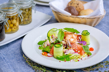 Salad with shrimp, grapefruit, cucumber, radish is served on a large white plate in the restaurant. Close-up. Restaurant menu.