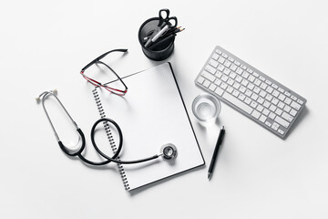 Composition with modern stethoscope and computer keyboard on light background