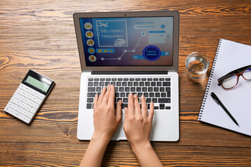 Female hands and laptop with open page of delivery service application on table