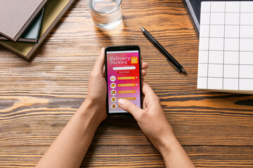 Female hands and mobile phone with open page of delivery service application on table