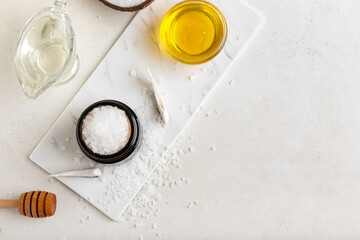 Jar with coconut body scrub and ingredients on light background