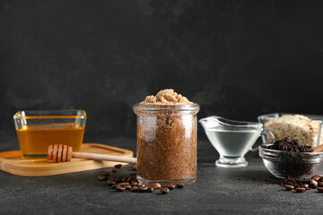 Jar of natural body scrub and ingredients on dark background