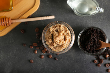 Jar of natural body scrub and ingredients on dark background