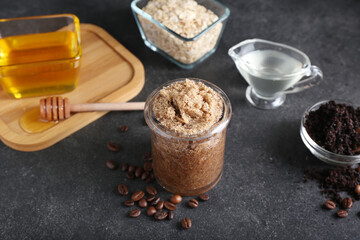 Jar of natural body scrub and ingredients on dark background