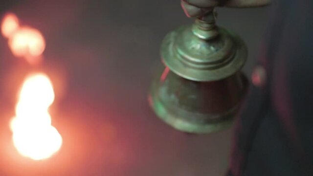 Close up of hand ringing metal bell in Indian ritual. Handheld, rack focus