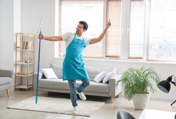 Fototapeta na wymiar Young man with floor mop in living room