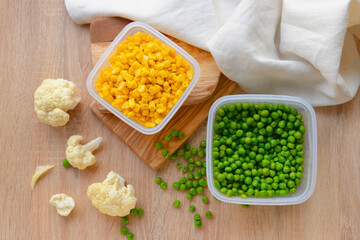 Plastic containers with vegetables on wooden background