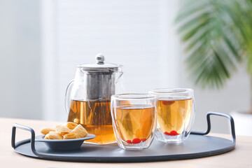 Teapot, glasses with hot tea and cookies on table in kitchen