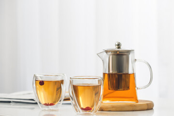 Teapot and glasses with hot tea on table in kitchen
