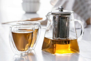 Teapot and glasses with hot tea on table in kitchen