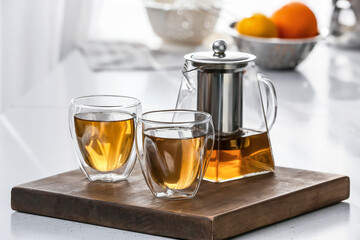 Teapot and glasses with hot tea on table in kitchen
