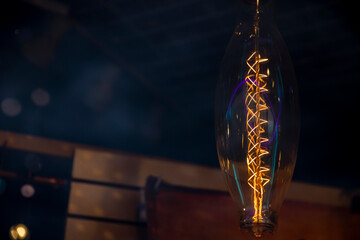 Edison victorian shaped light bulb visible filaments over a dark background - obrazy, fototapety, plakaty