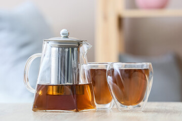 Teapot and glasses with hot tea on table in kitchen