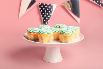 Dessert stand with tasty birthday cupcakes on color background