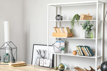 Modern book shelf with decor near light wall