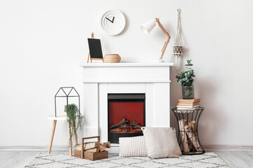 Modern fireplace with firewood near light wall