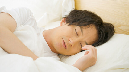 Fototapeta na wymiar ベッドで眠る男性