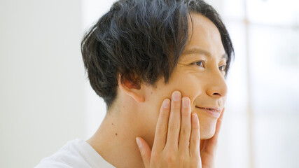 笑顔で顔を触る男性