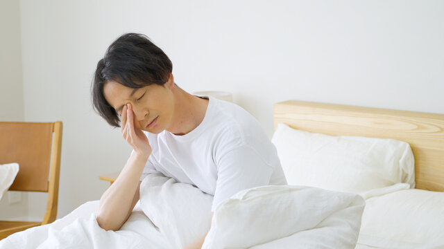 朝ベッドから起きる男性
