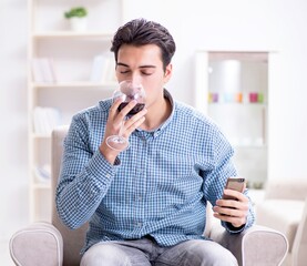 Young man drinking wine at home