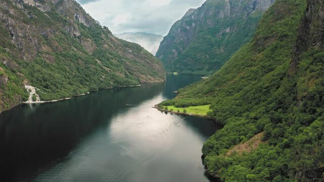 A magnificent view of the Naeroyfjord. UNESCO heritage site and one of the most beautiful fjords in Norway. Forest-covered mountains tower above the narrow waterway. Ripples run on the water surface.